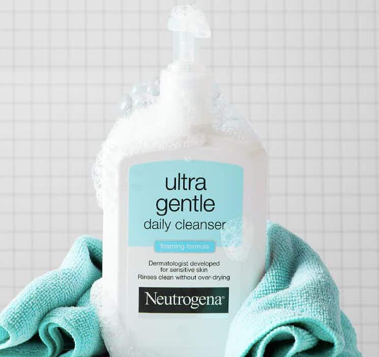 bottle of neutrogena ultra gentle face cleanser covered in suds with a blue towel