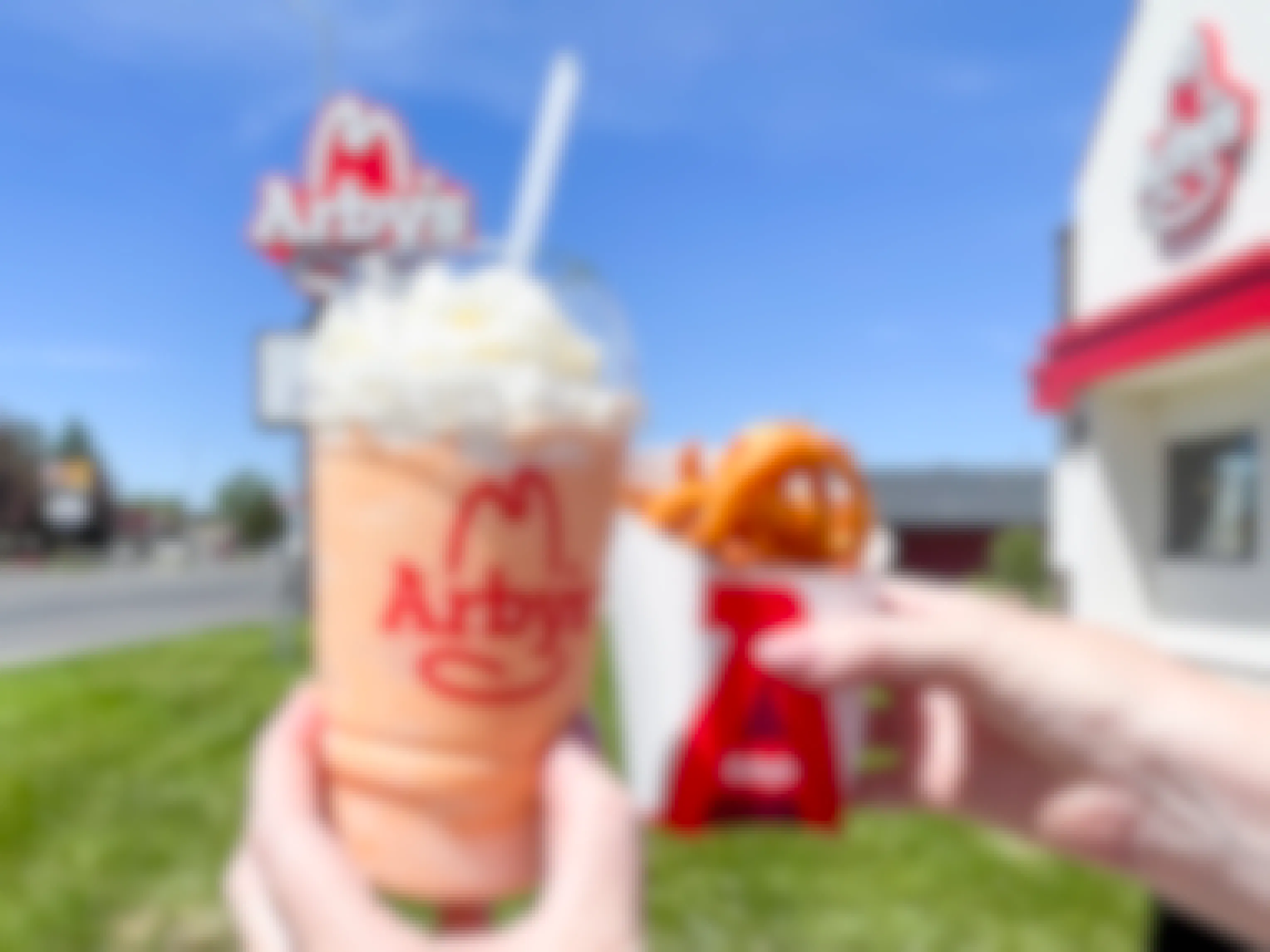 a shake and fries being held outside arbys 
