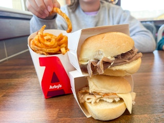 a person eating fires next to two arbys slider 