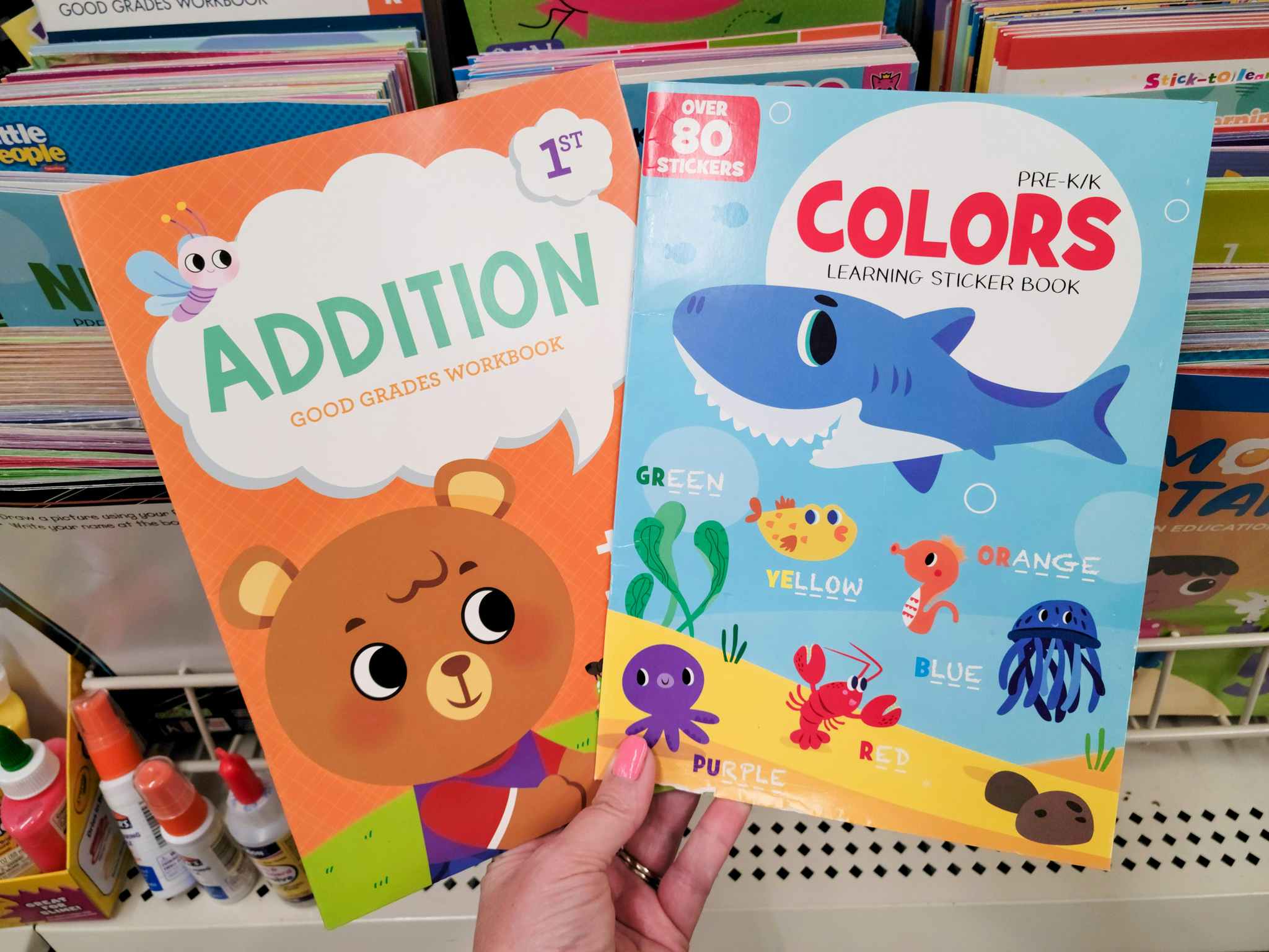 hand holding an addition activity book and a color activity book