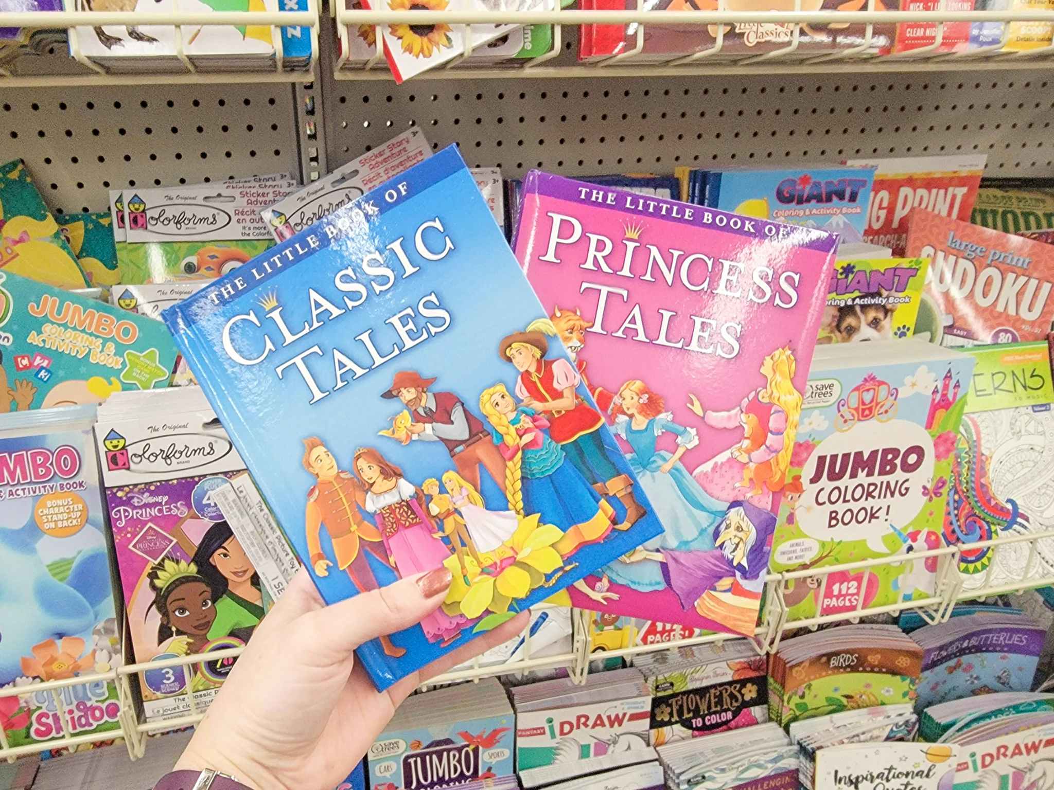 hand holding 2 kids books: classic tales and princess tales
