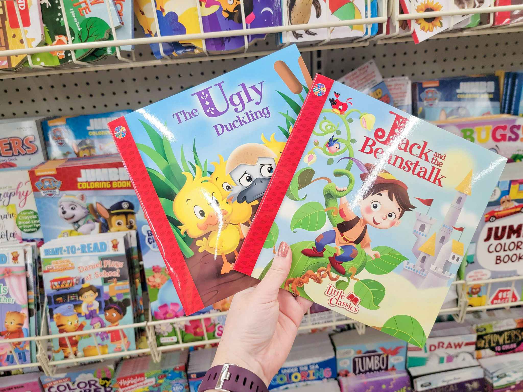 hand holding 2 kids books: the ugly duckling and jack and the beanstalk