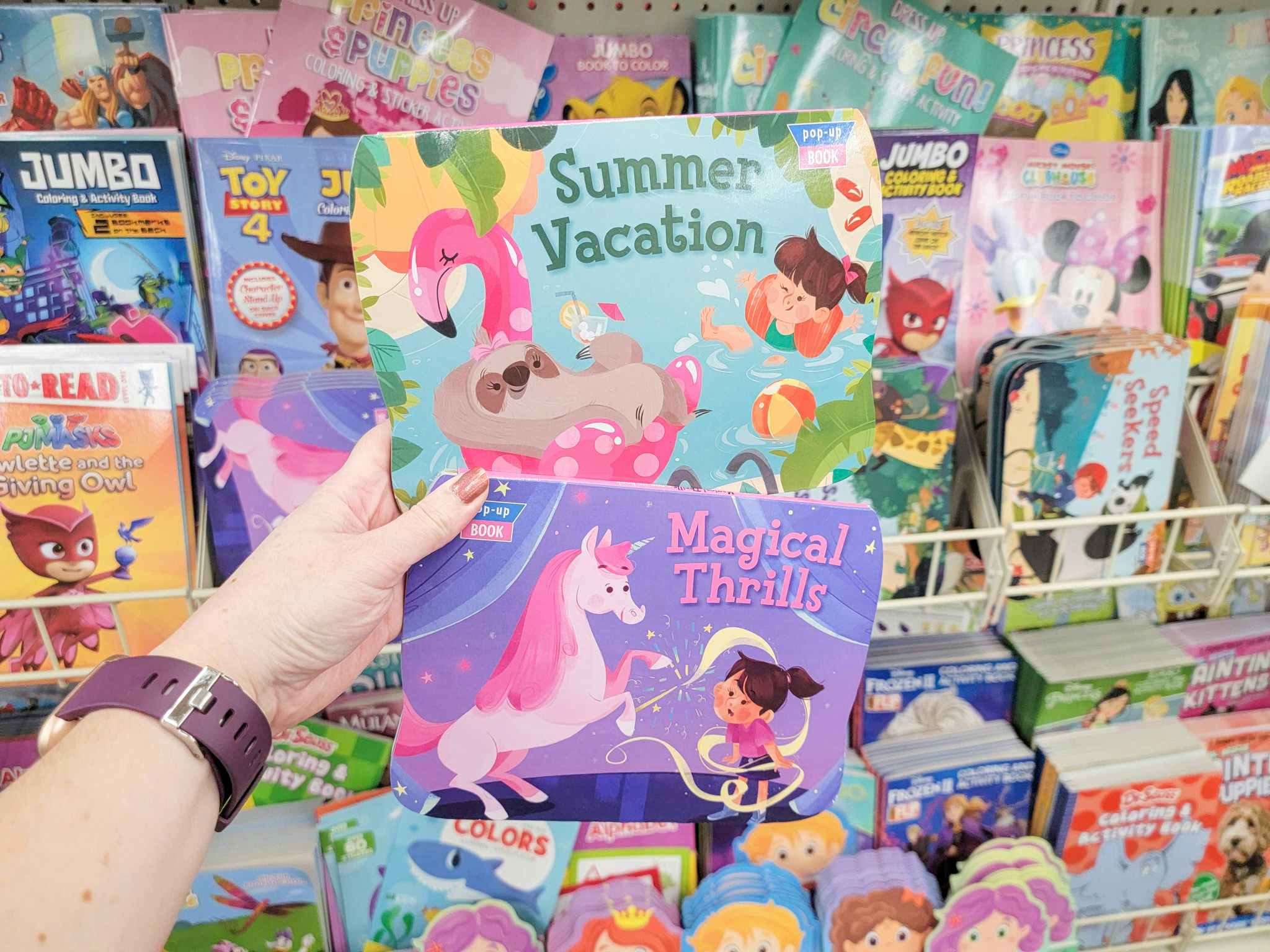 hand holding 2 pop-up kids books: summer vacation and magical thrills