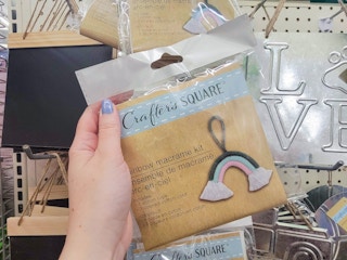 hand holding up a mini macrame rainbow craft kit