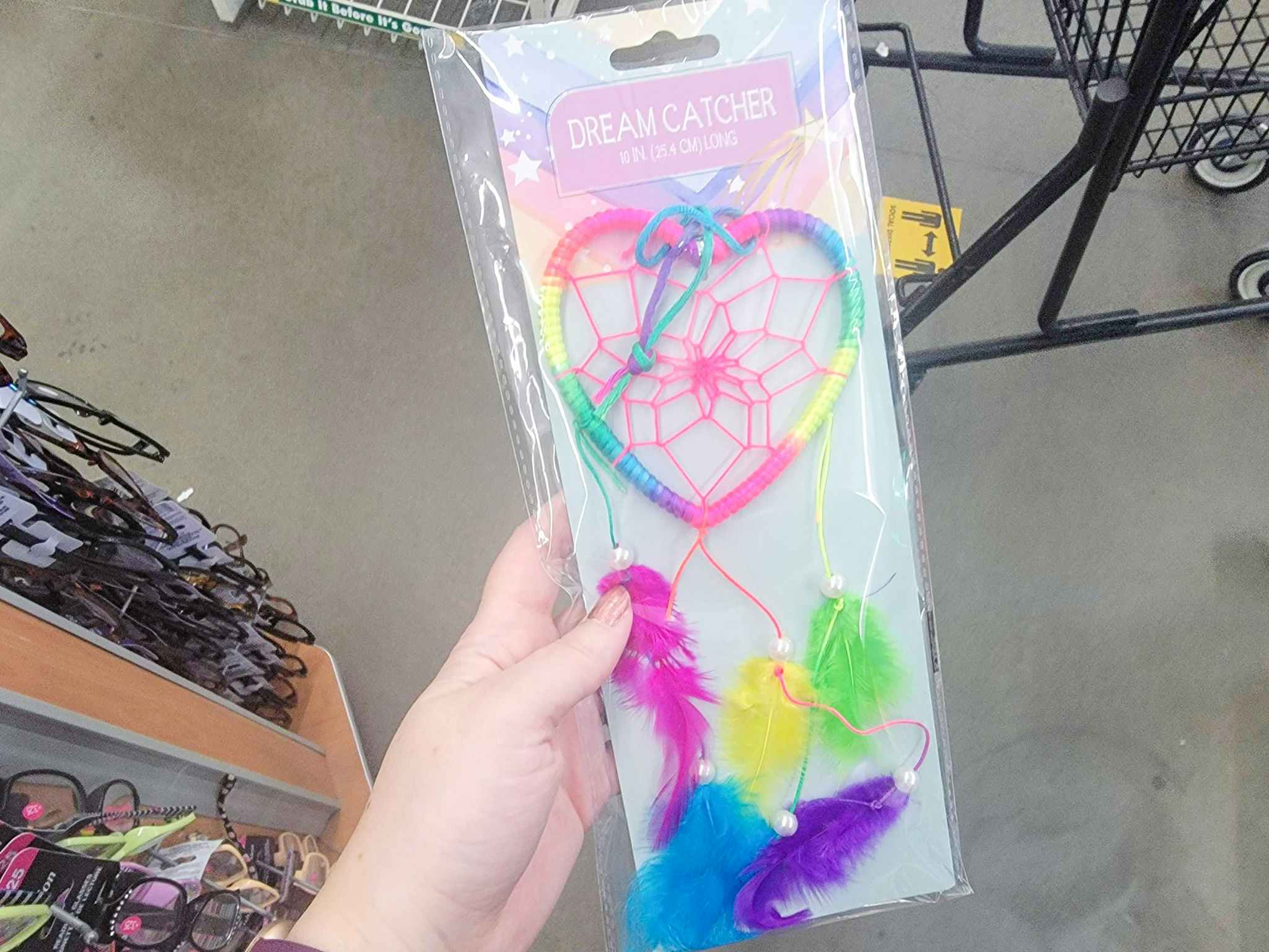 hand holding a heart shaped rainbow colored dream catcher