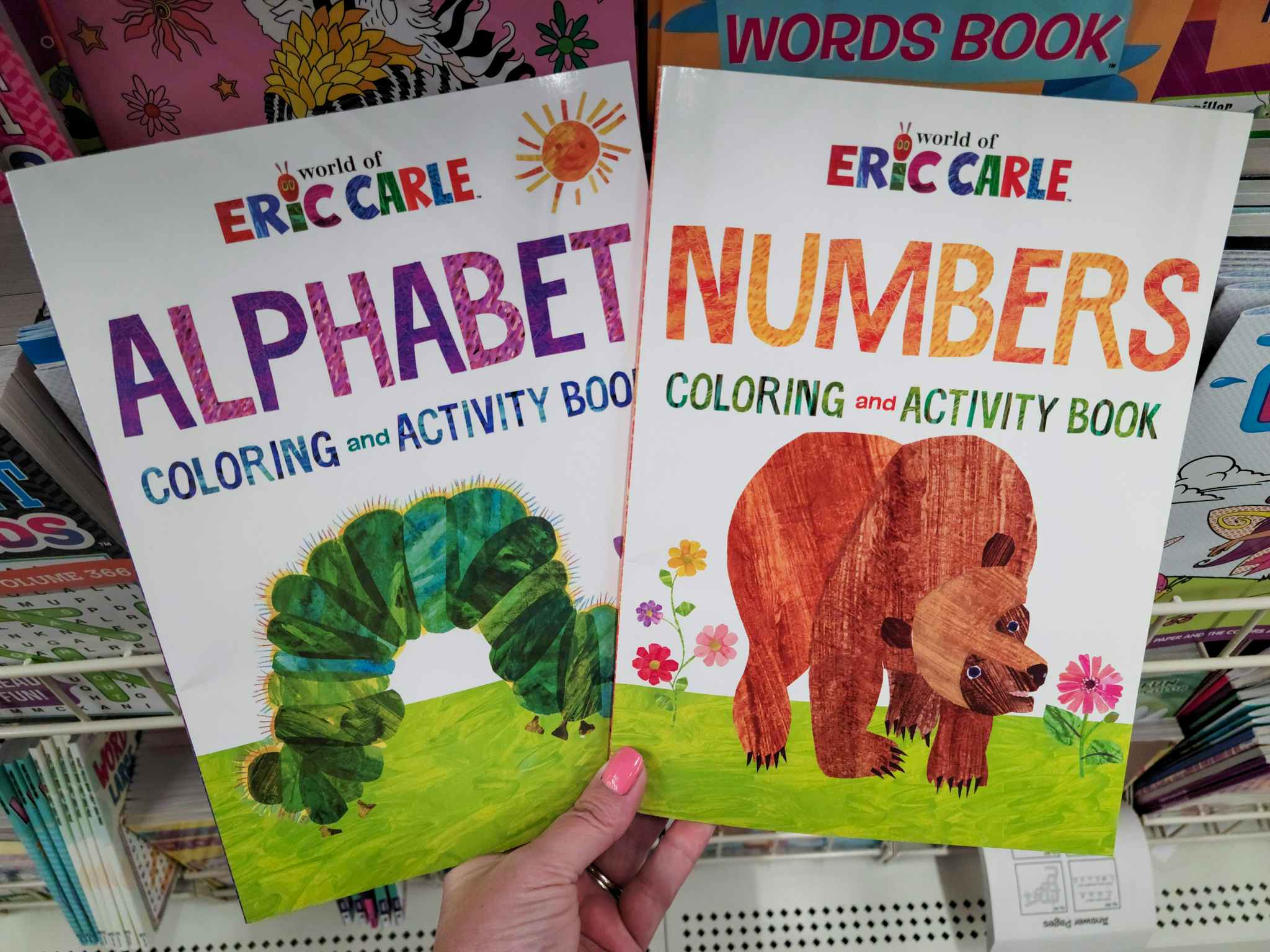hand holding two eric carle activity books, alphabet and numbers