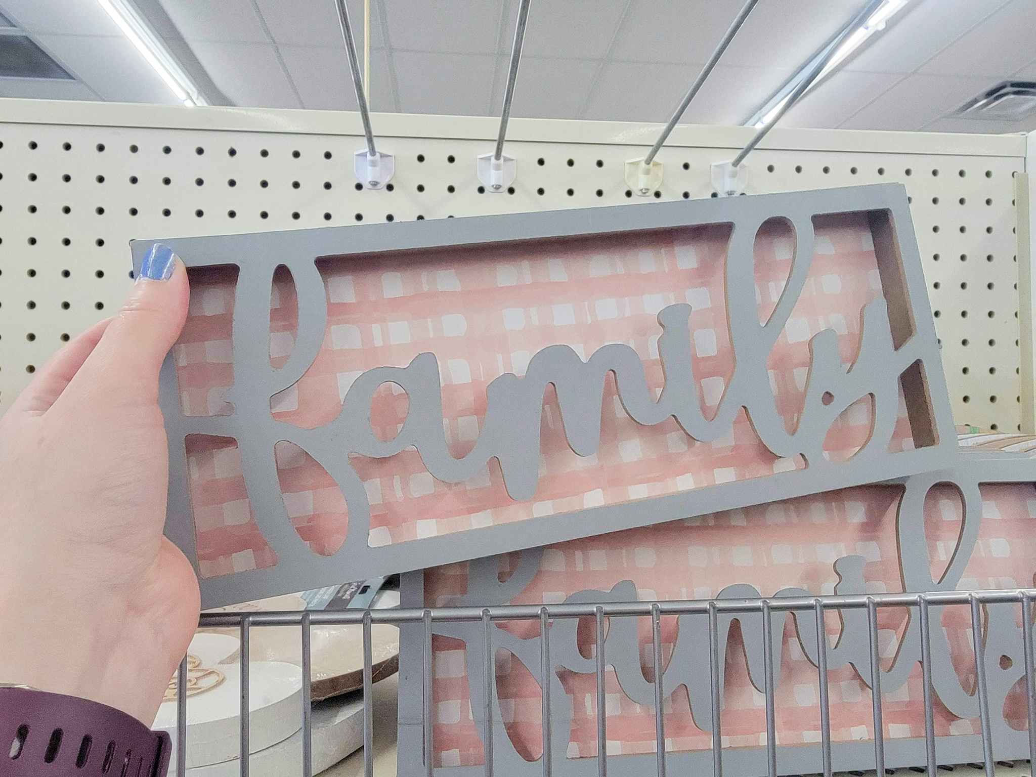 hand holding a pink and grey "family" sign