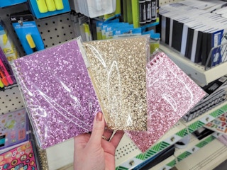 hand holding three glittery notebooks