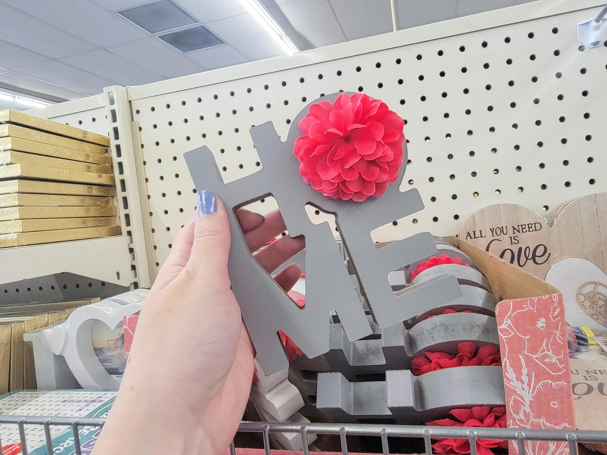 hand holding a grey "home" tabletop decor with a pink flower on the "o