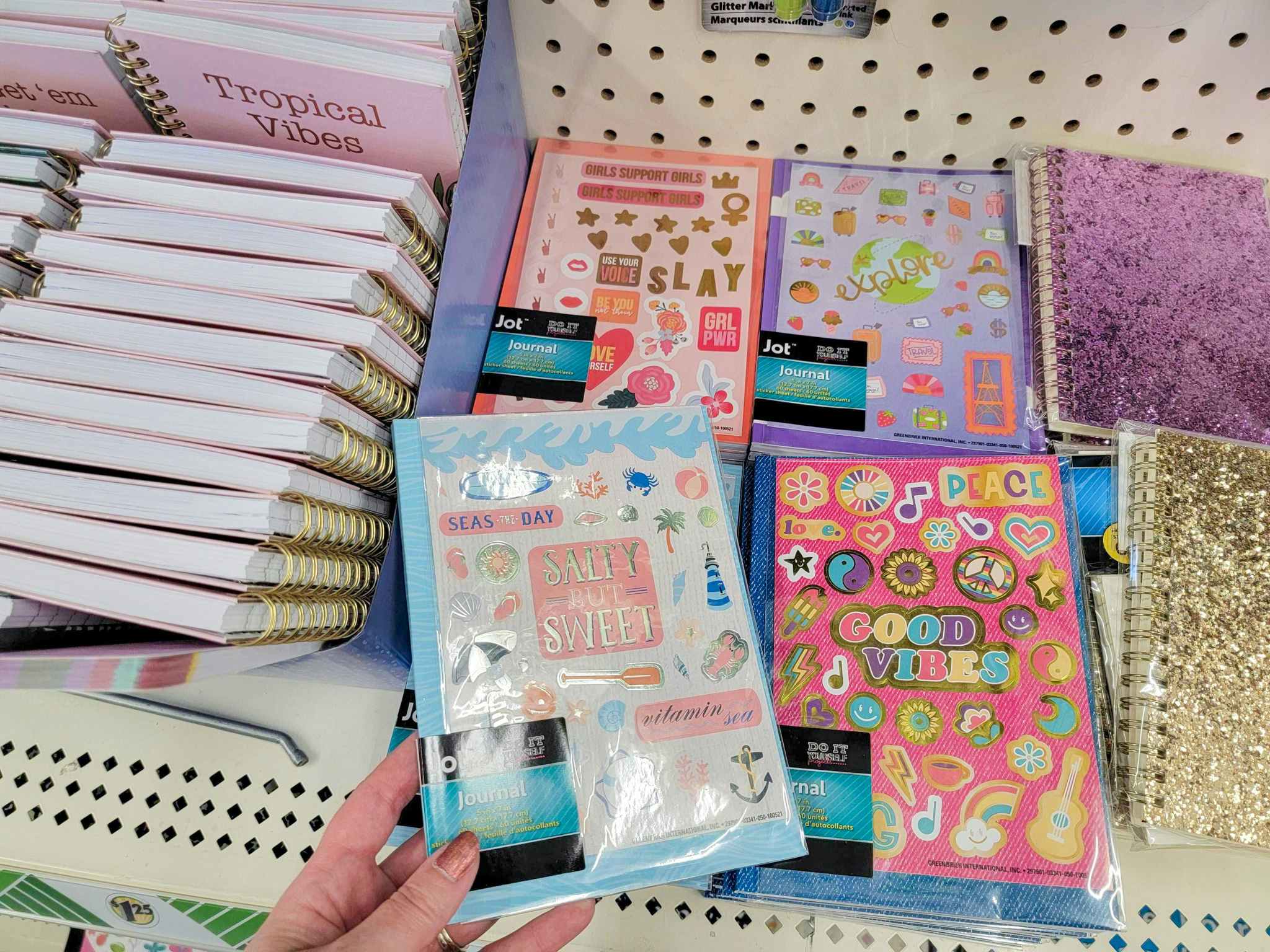 hand holding a journal with sticker over other journals