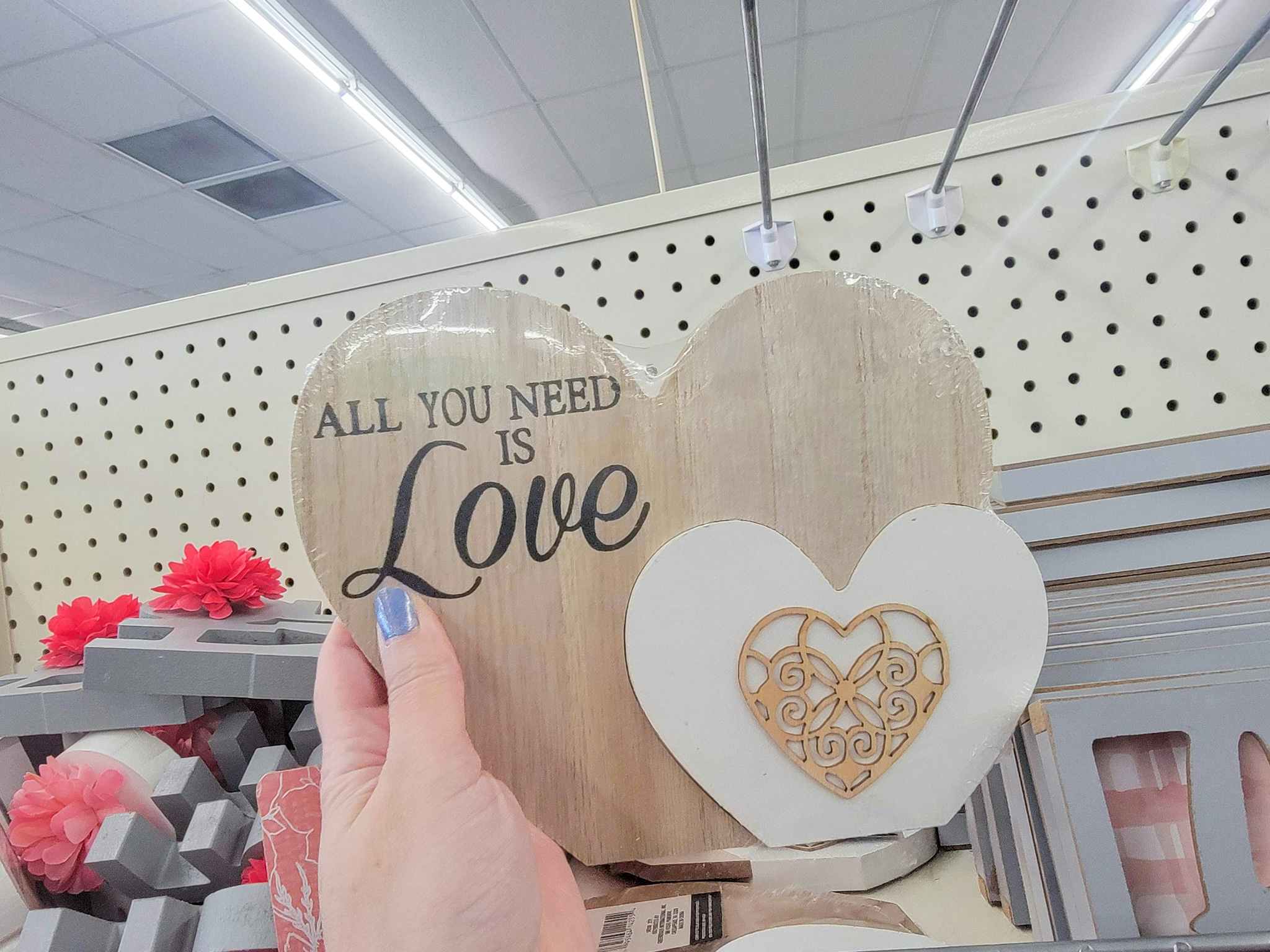 hand holding a wooden heart that says "all you need is love