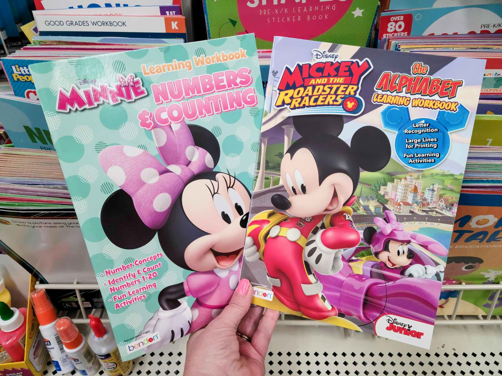 hand holding minnie and mickey mouse activity books