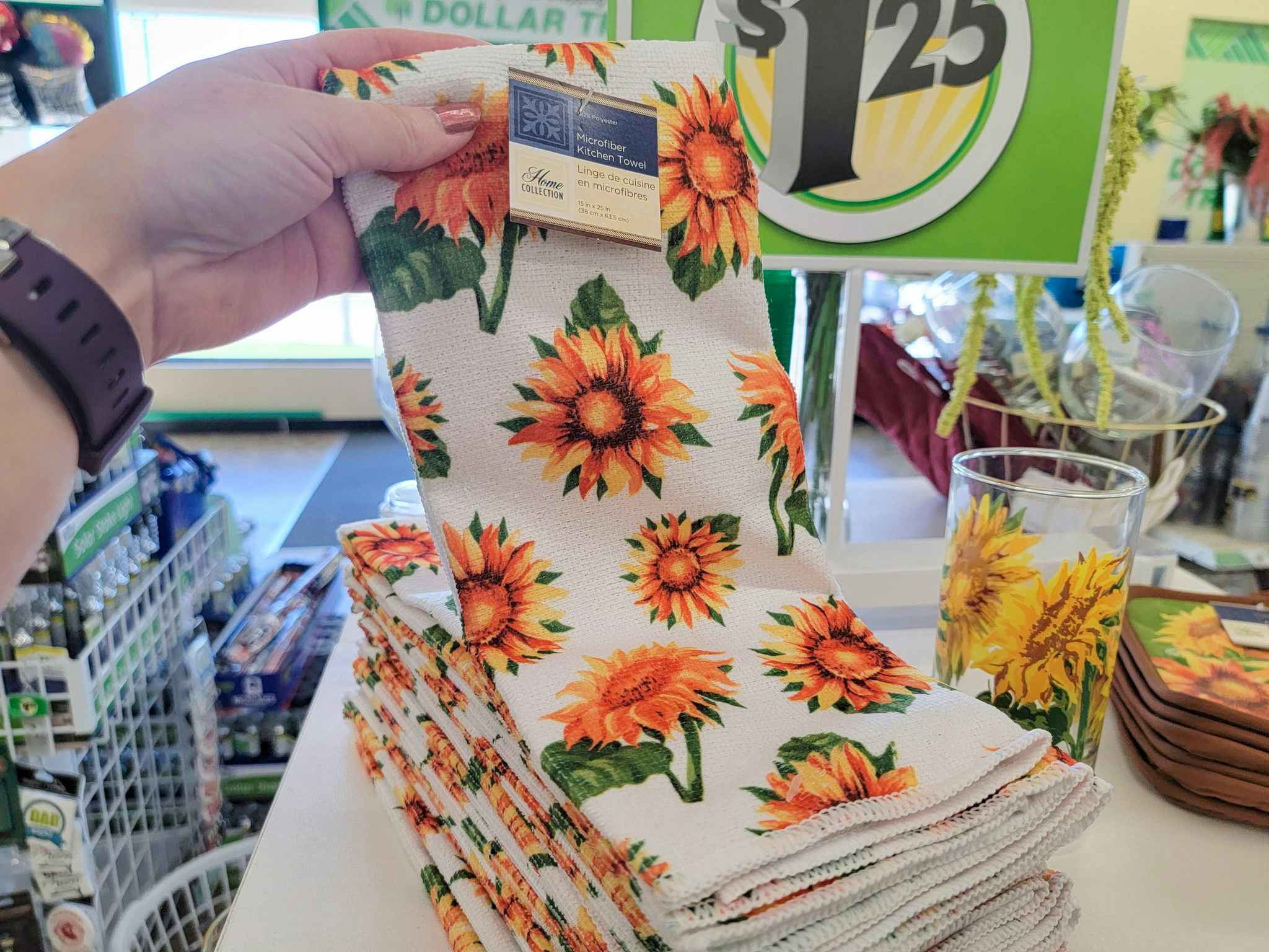 hand holding up a kitchen towel with sunflowers on it