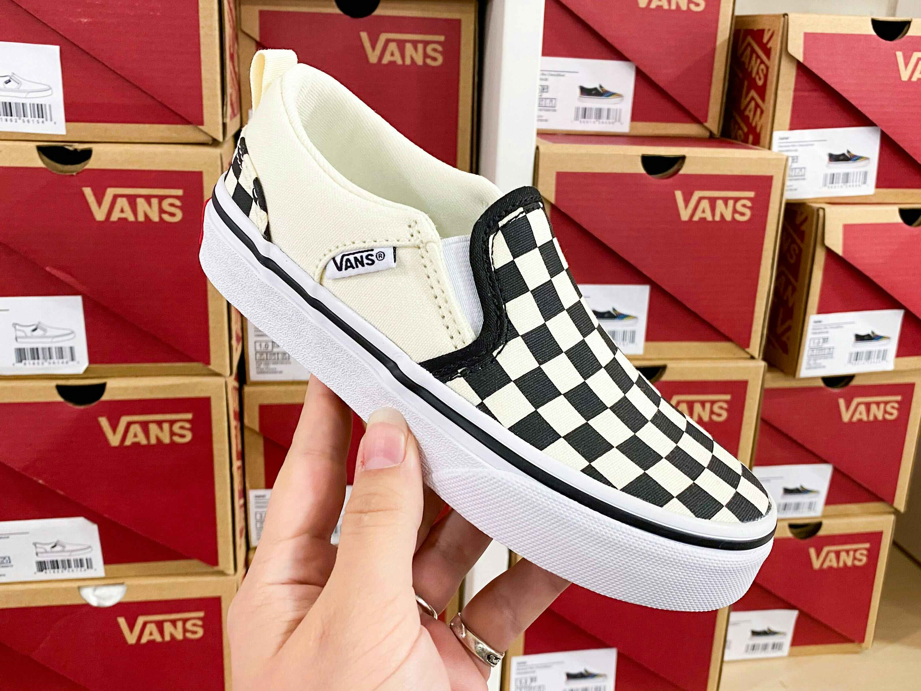 someone holding up a vans checkered shoe