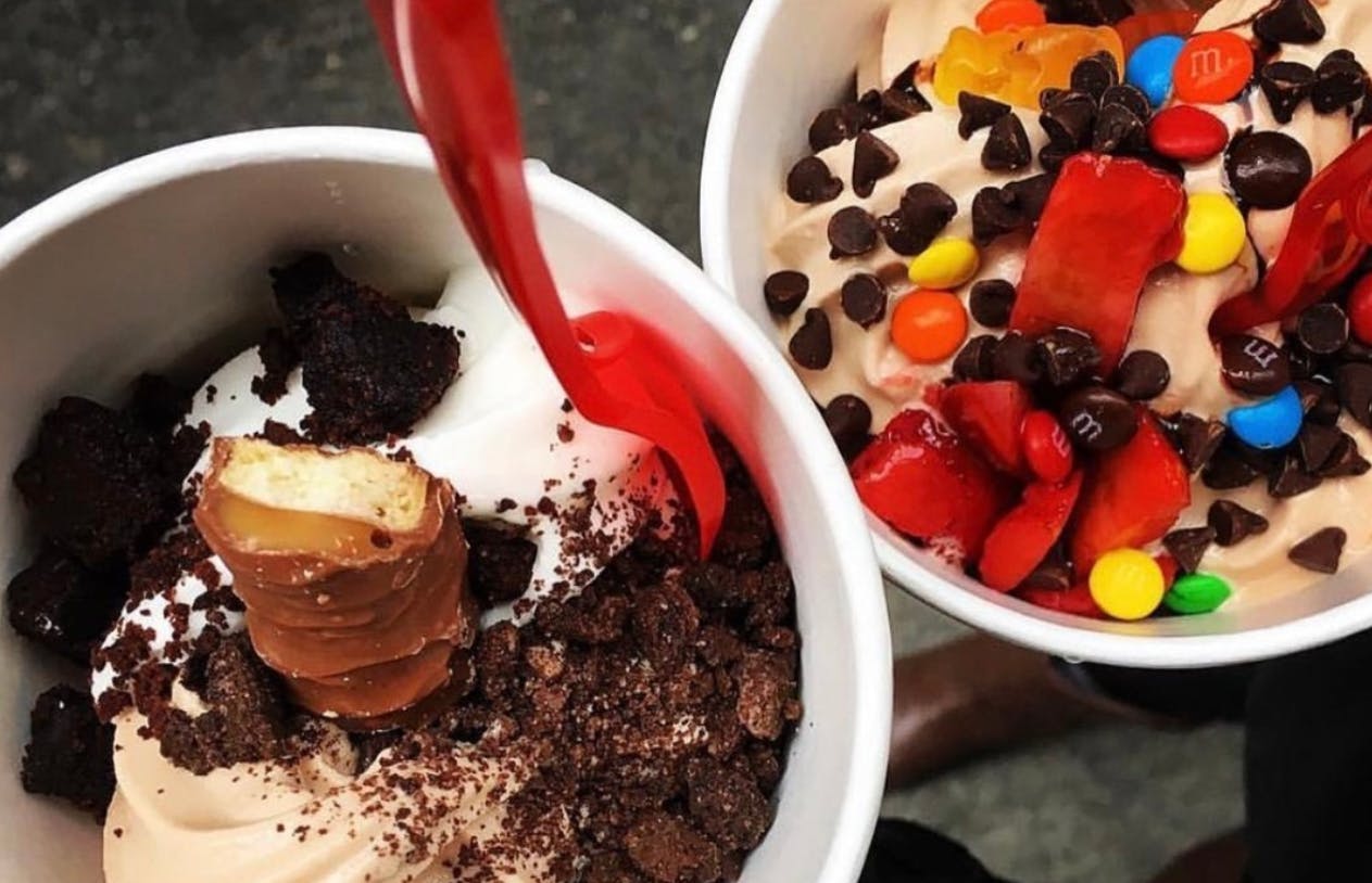 Two frozen yogurts from Red Mango with toppings including a Twix bar and mini chocolate chips.