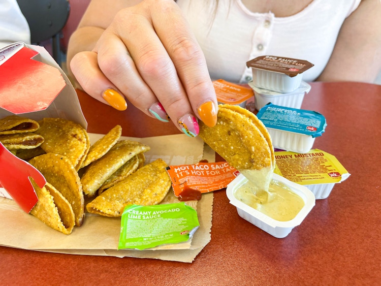 a person dipping mini tacos into sauce