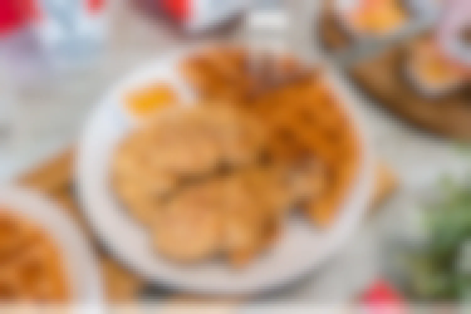 A plate of Chicken and waffles with KFC cup, and food container in the background.