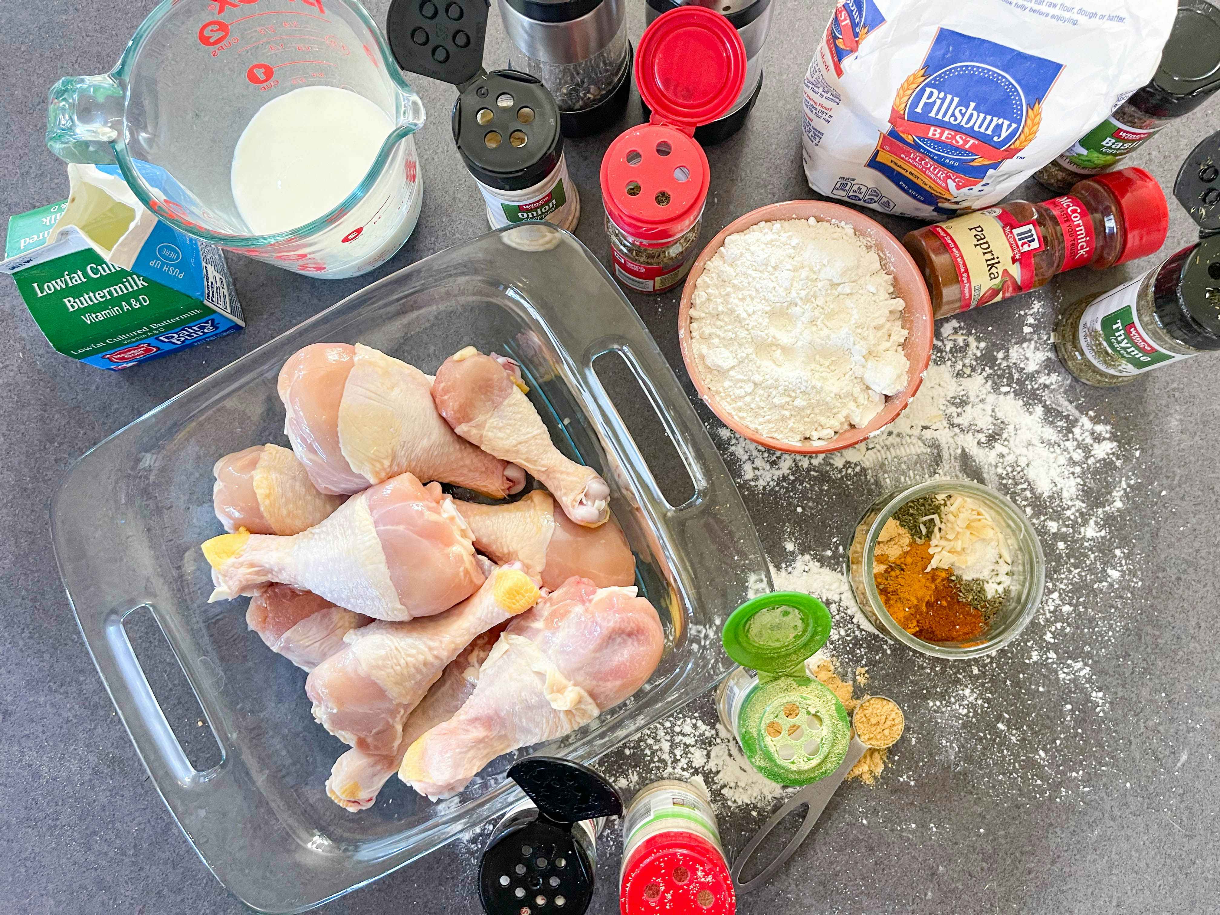 diy chicken seasonings, flour, ingredients, and raw drumsticks on counter