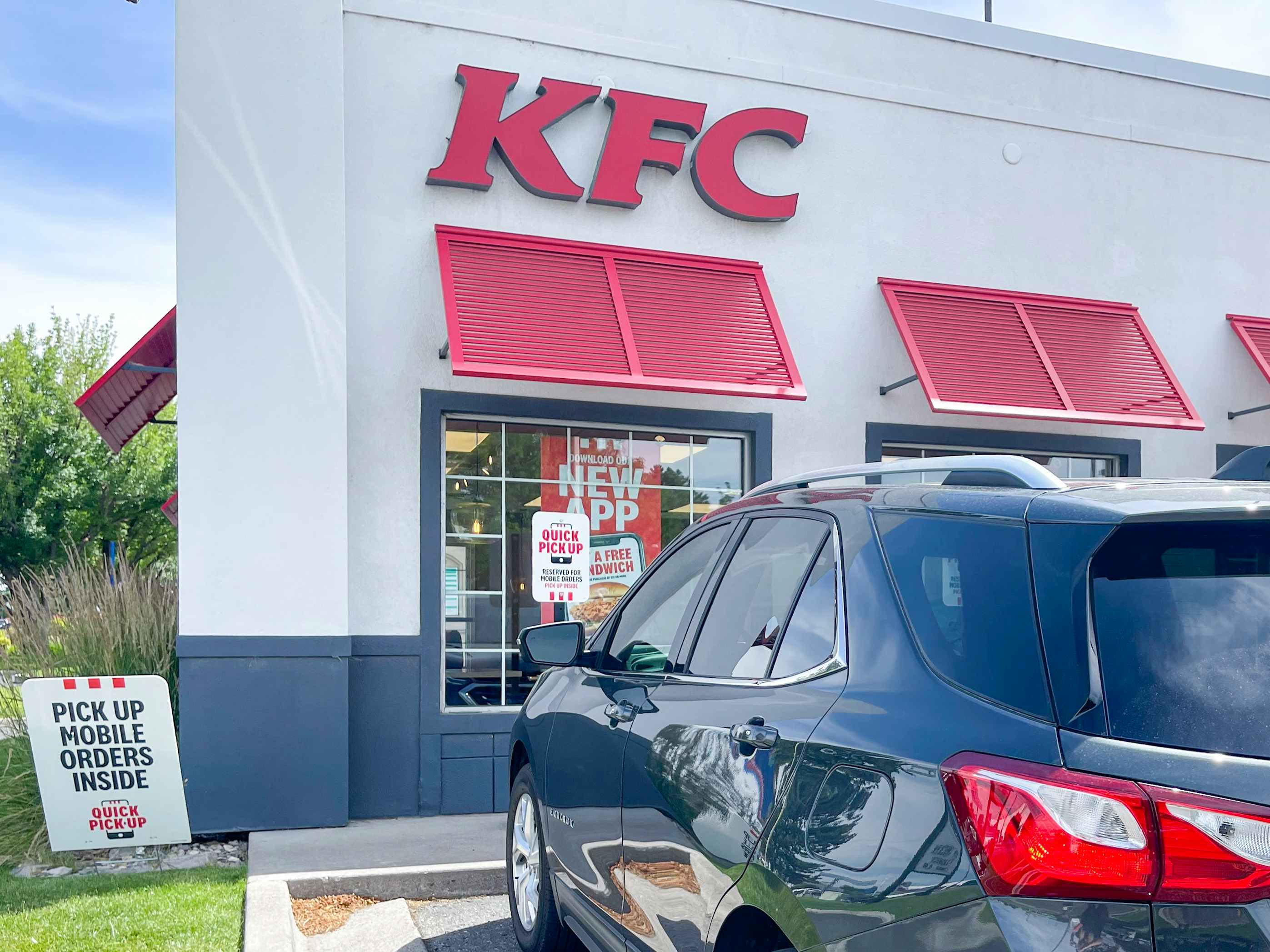 A KFC restaurant exterior with a car parked in front.