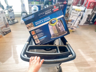 woman pushing a cart at kohl's with a bissell upholstery and carpet cleaner inside the cart
