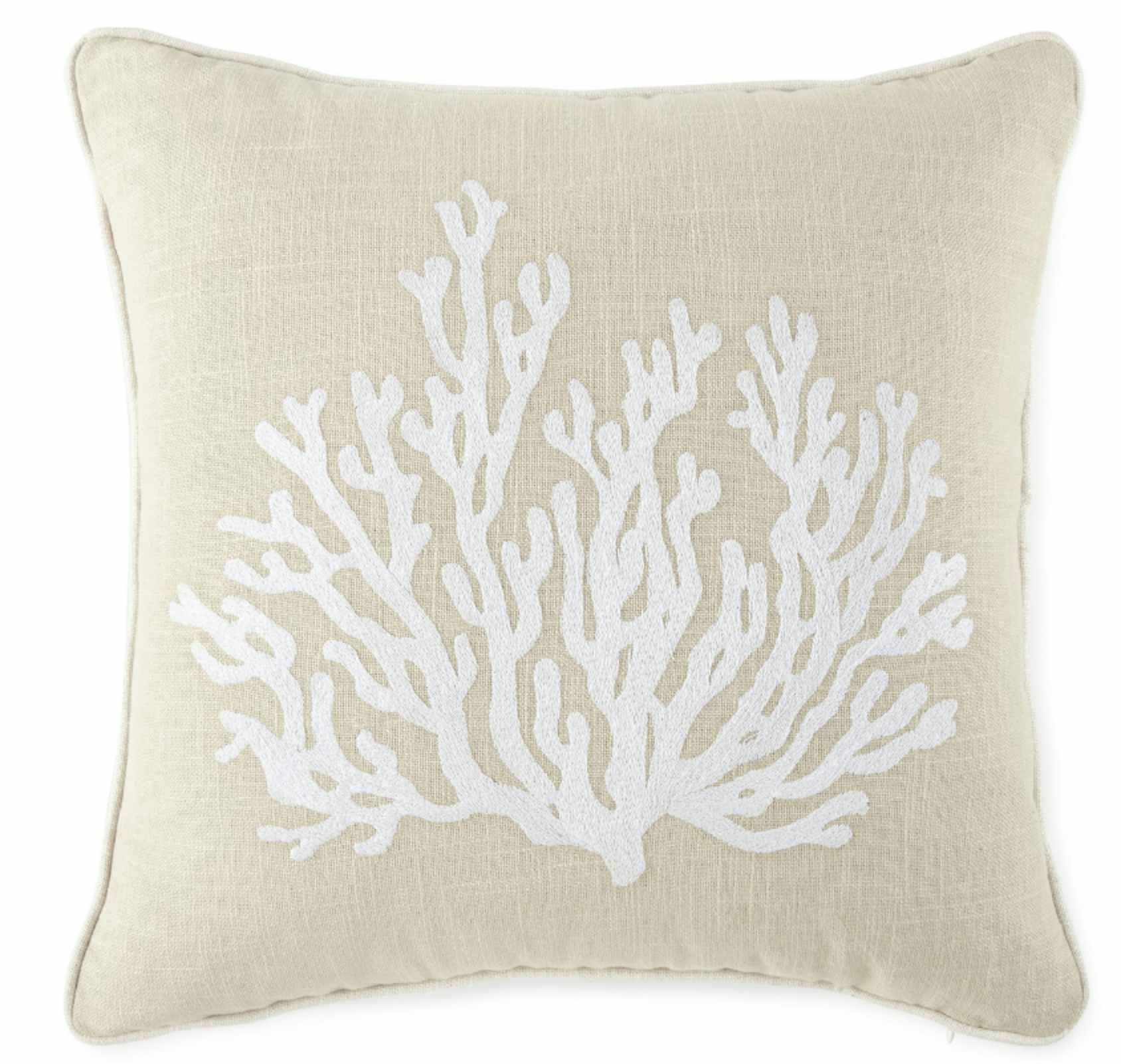 a cream throw pillow with white coral on it