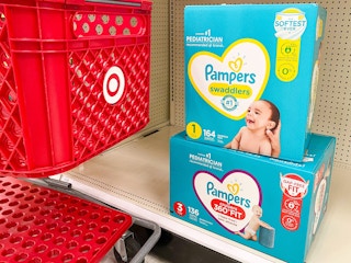 Two boxes of Pampers diapers on store shelf next to Target shopping cart
