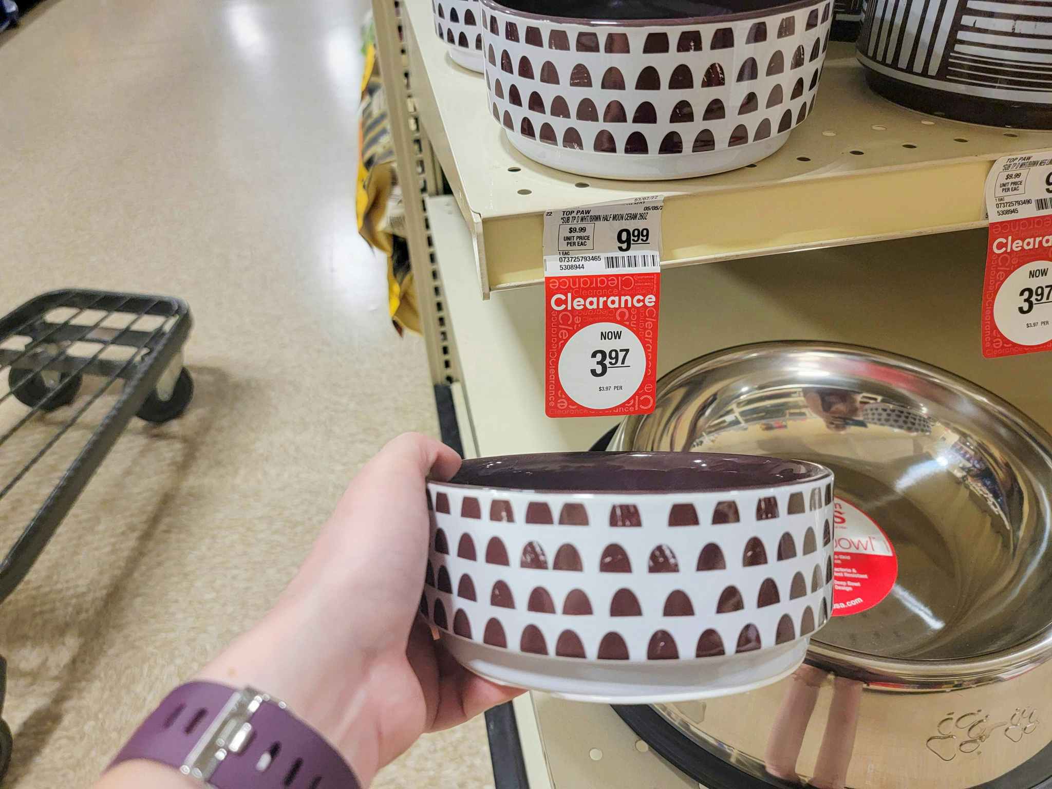 hand holding a white with brown spots dog bowl