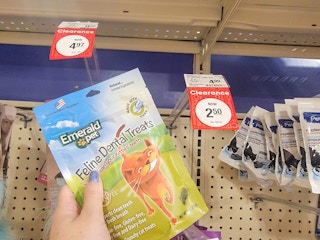 a hand holding a bag of cat dental treats by the clearance tag