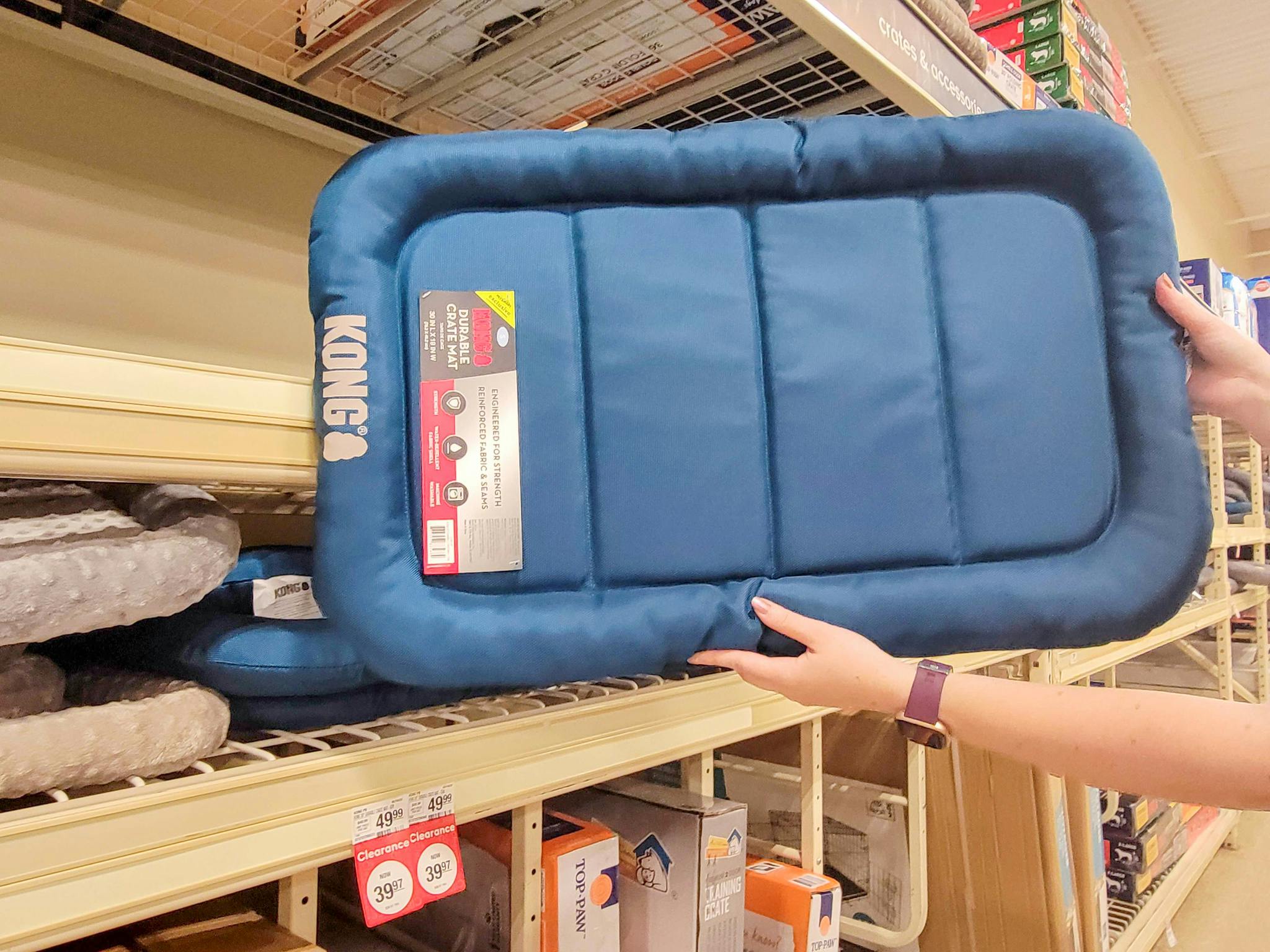 Hands holding teal Kong crate mat at Petsmart