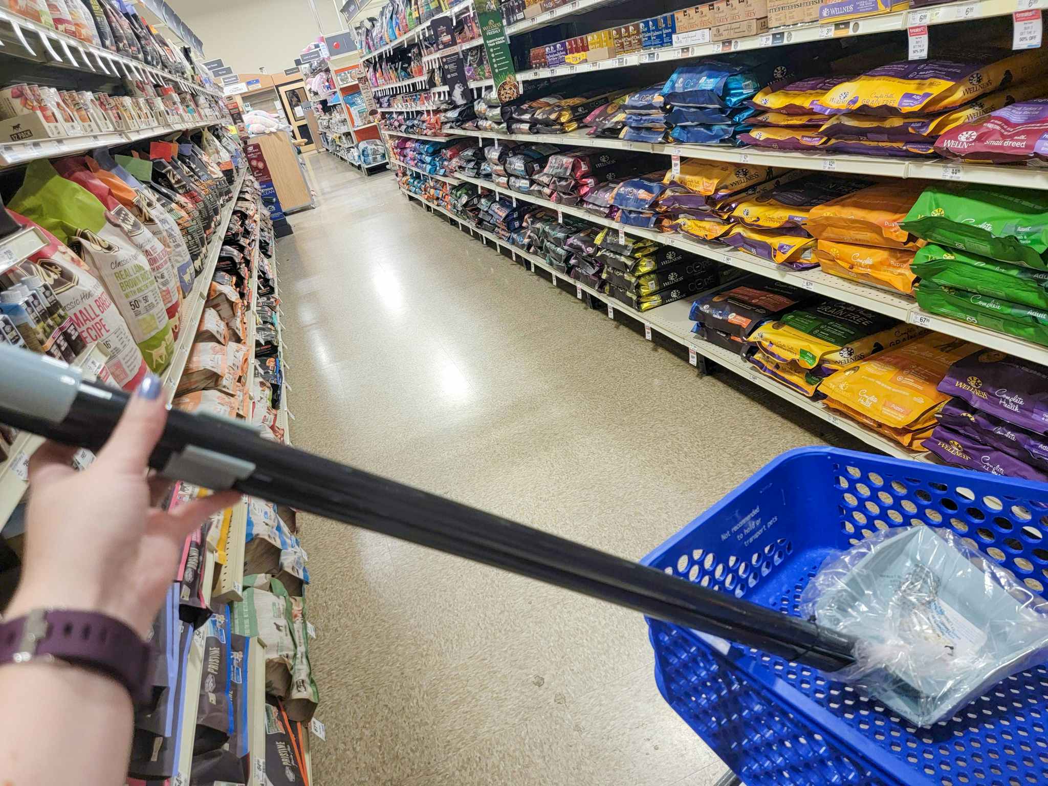 hand holding a blue pooper scooper sitting in a cart
