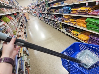 hand holding a blue pooper scooper sitting in a cart