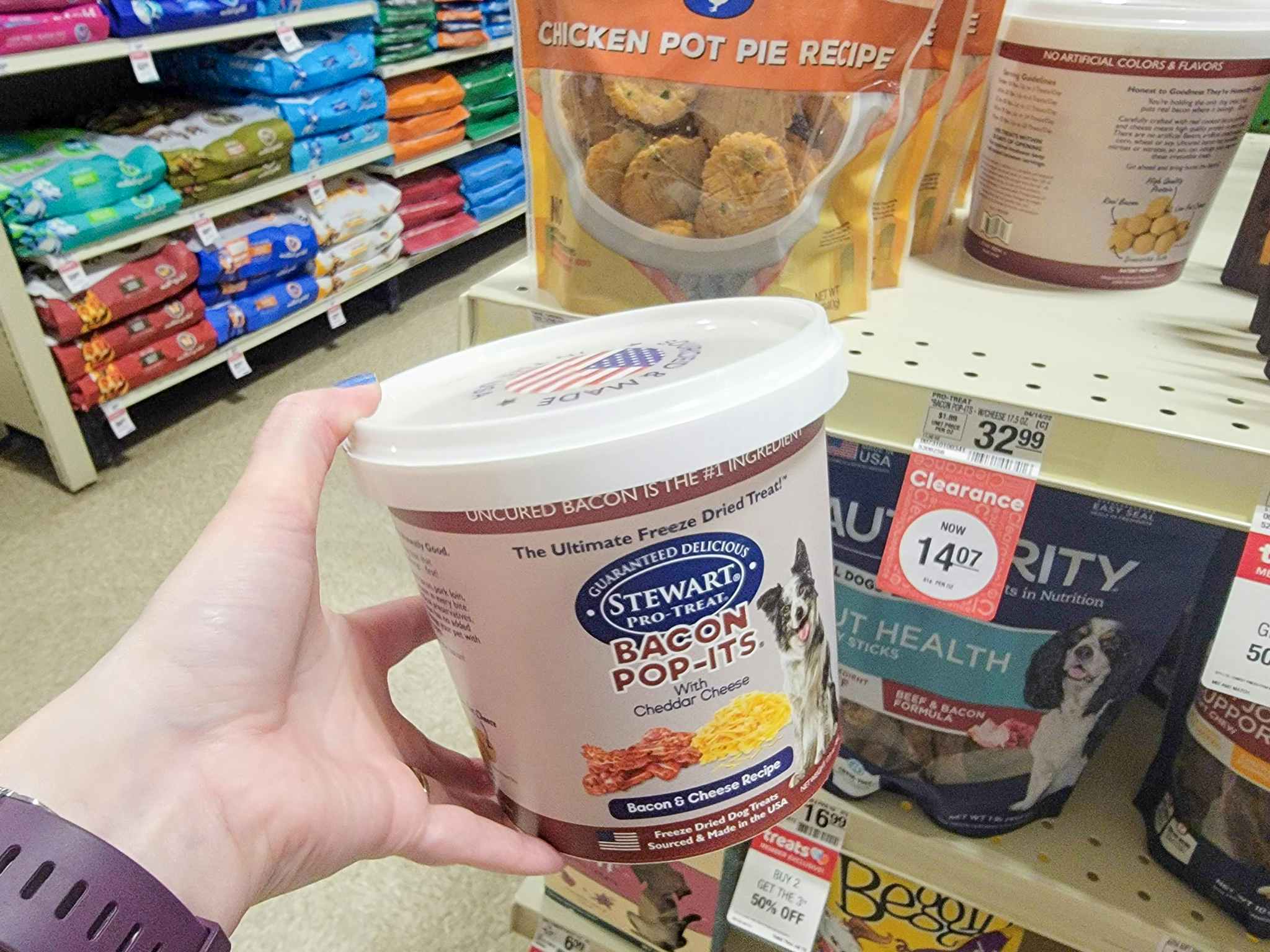 hand holding a container of bacon cheddar dog treats