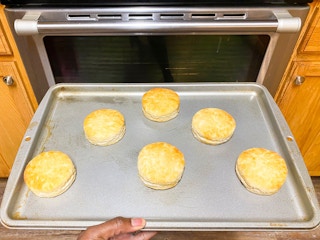 A baking sheet of biscuits being taken out of an oven.