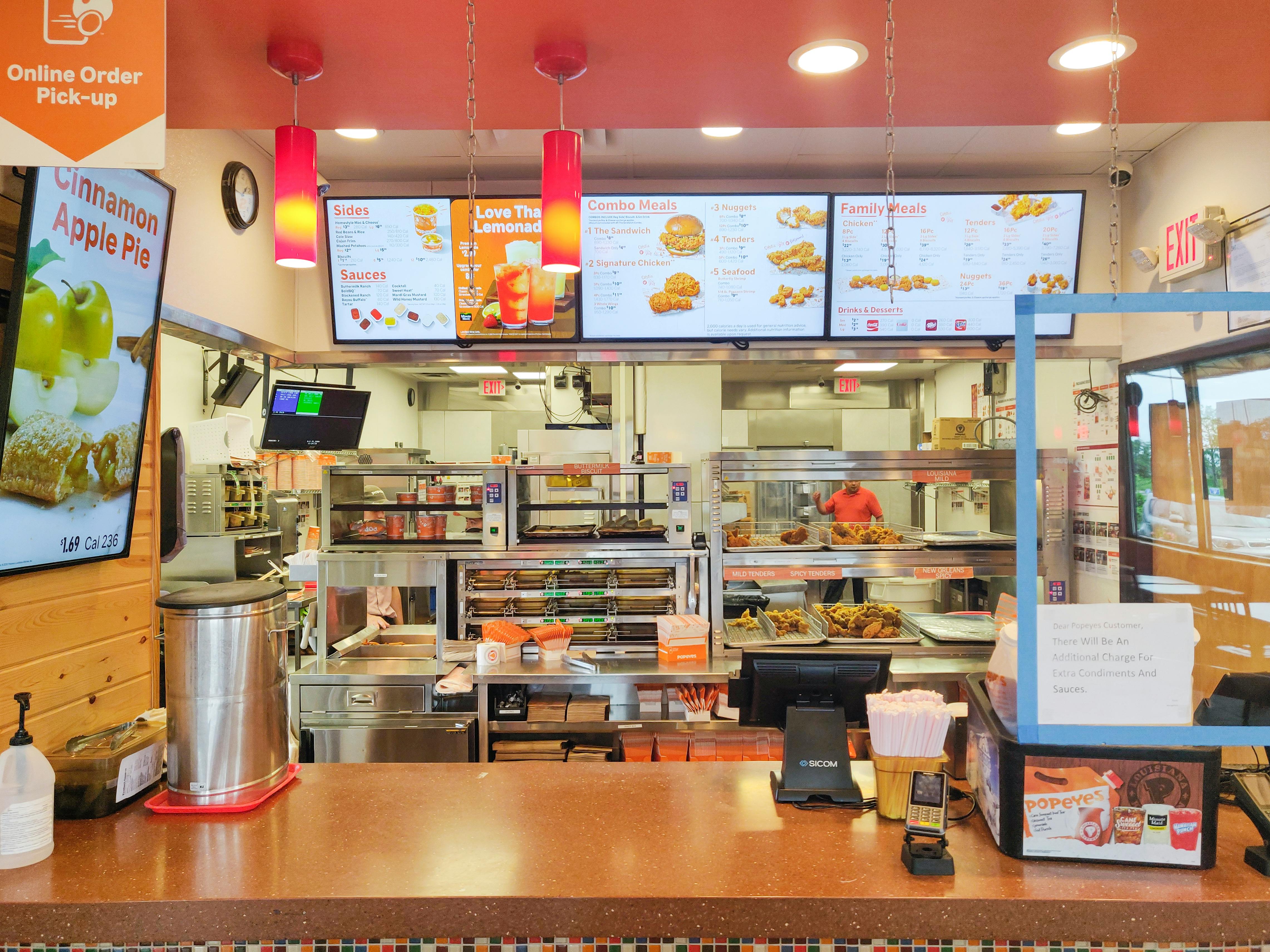 Popeyes checkout counter with kitchen and menu in background