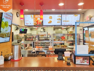 Popeyes checkout counter with kitchen and menu in background