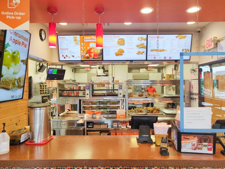 Popeyes checkout counter with kitchen and menu in background