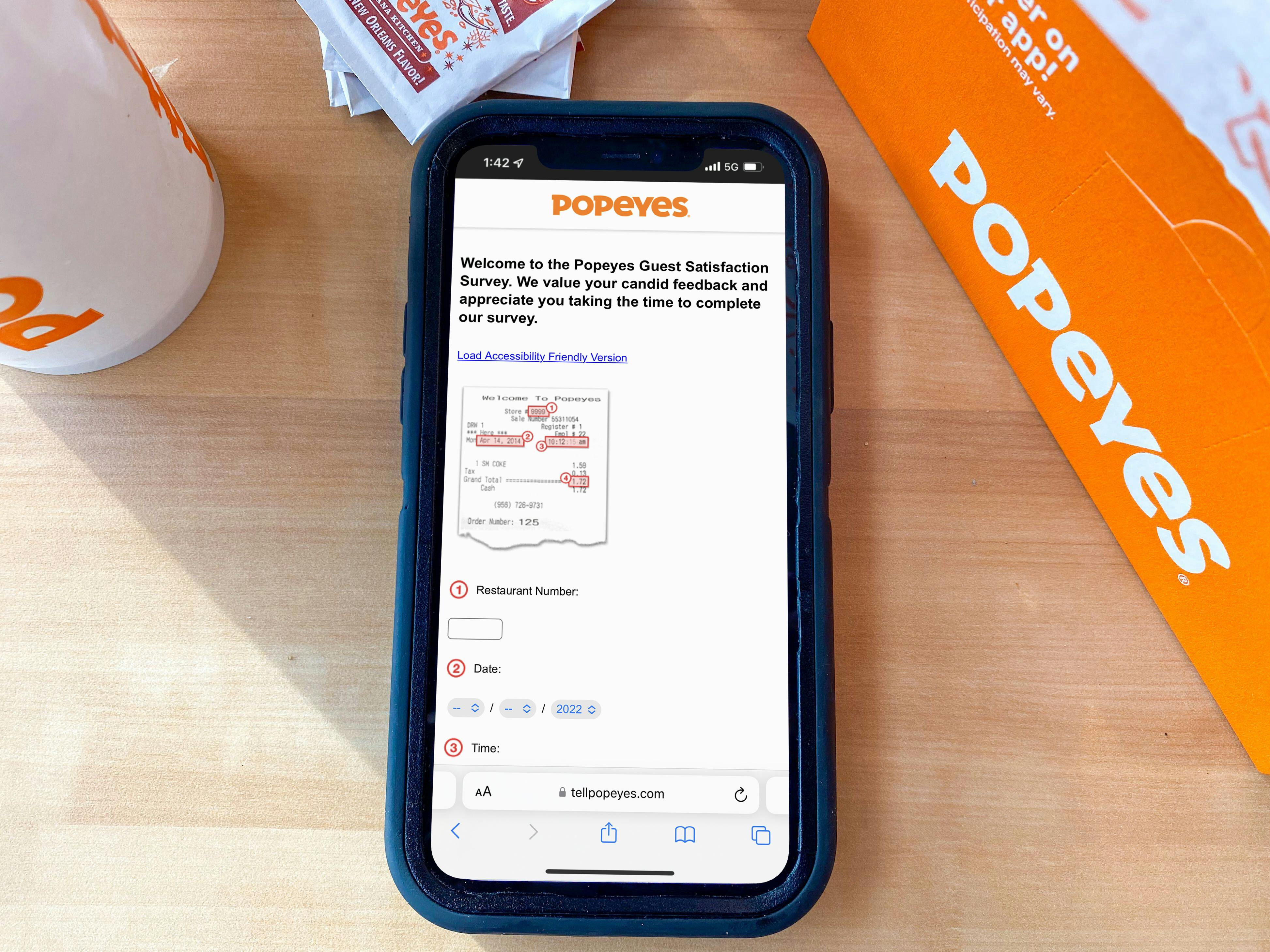 A Popeyes survey displayed on an iPhone that is on a table next to some Popeyes food containers.
