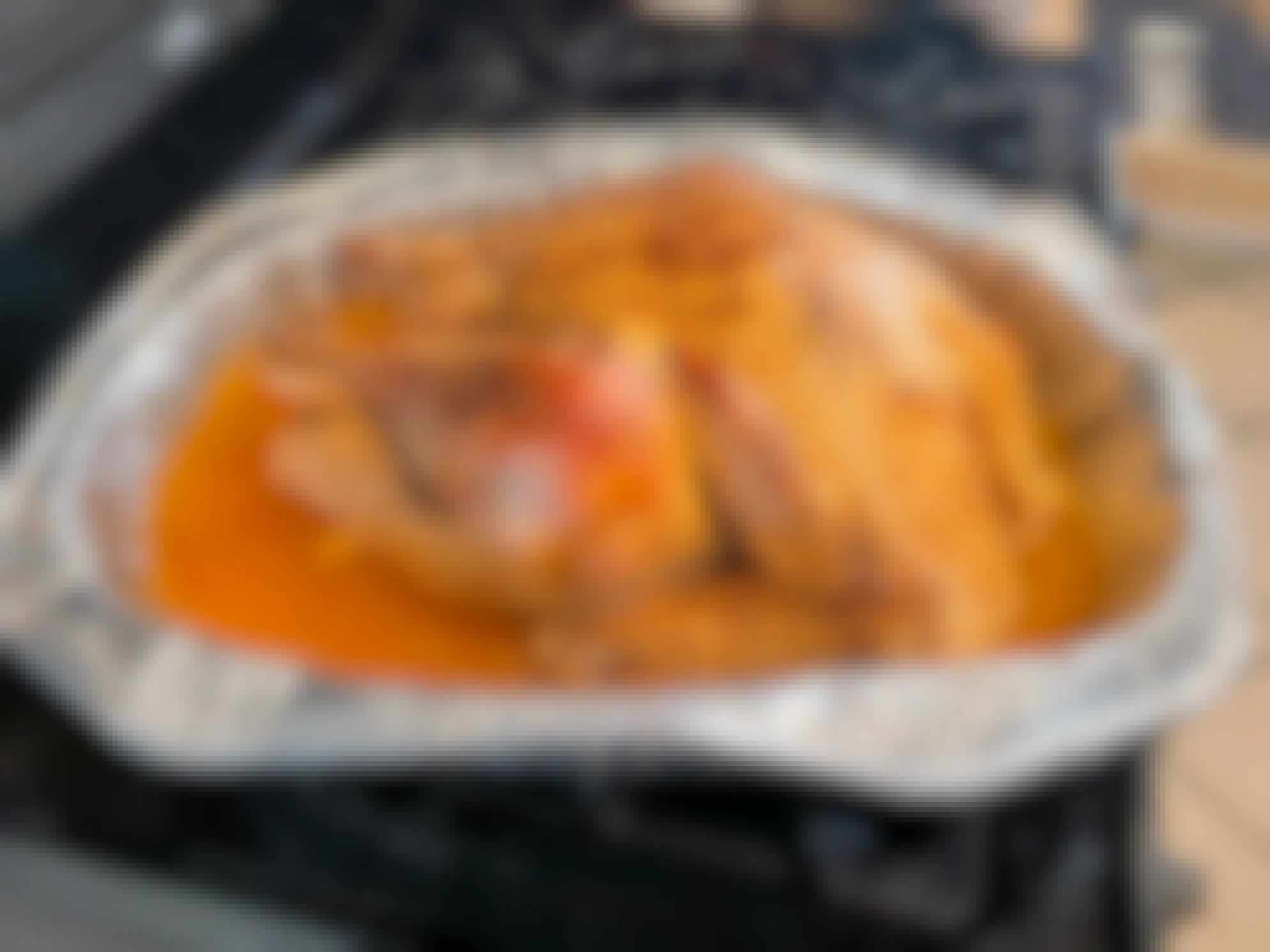 A cooked turkey in an aluminum baking dish, sitting on a stove.
