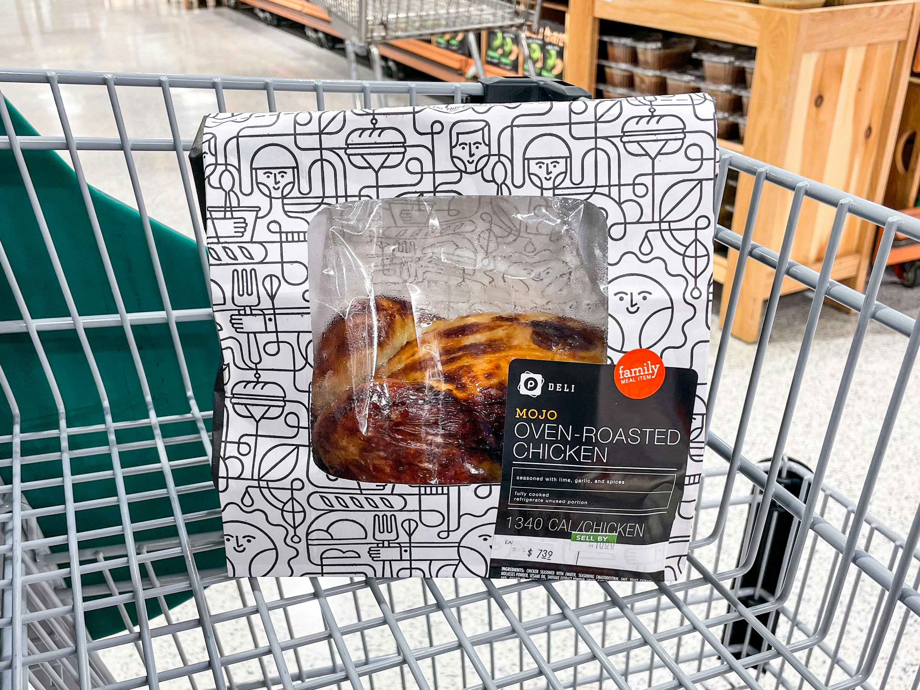 A packaged mojo rotisserie chicken sitting in a shopping cart inside Publix.