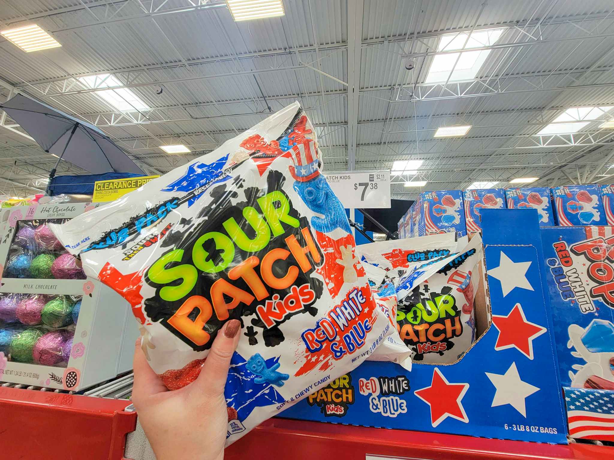 hand holding a bag of red, white, and blue sour patch kids
