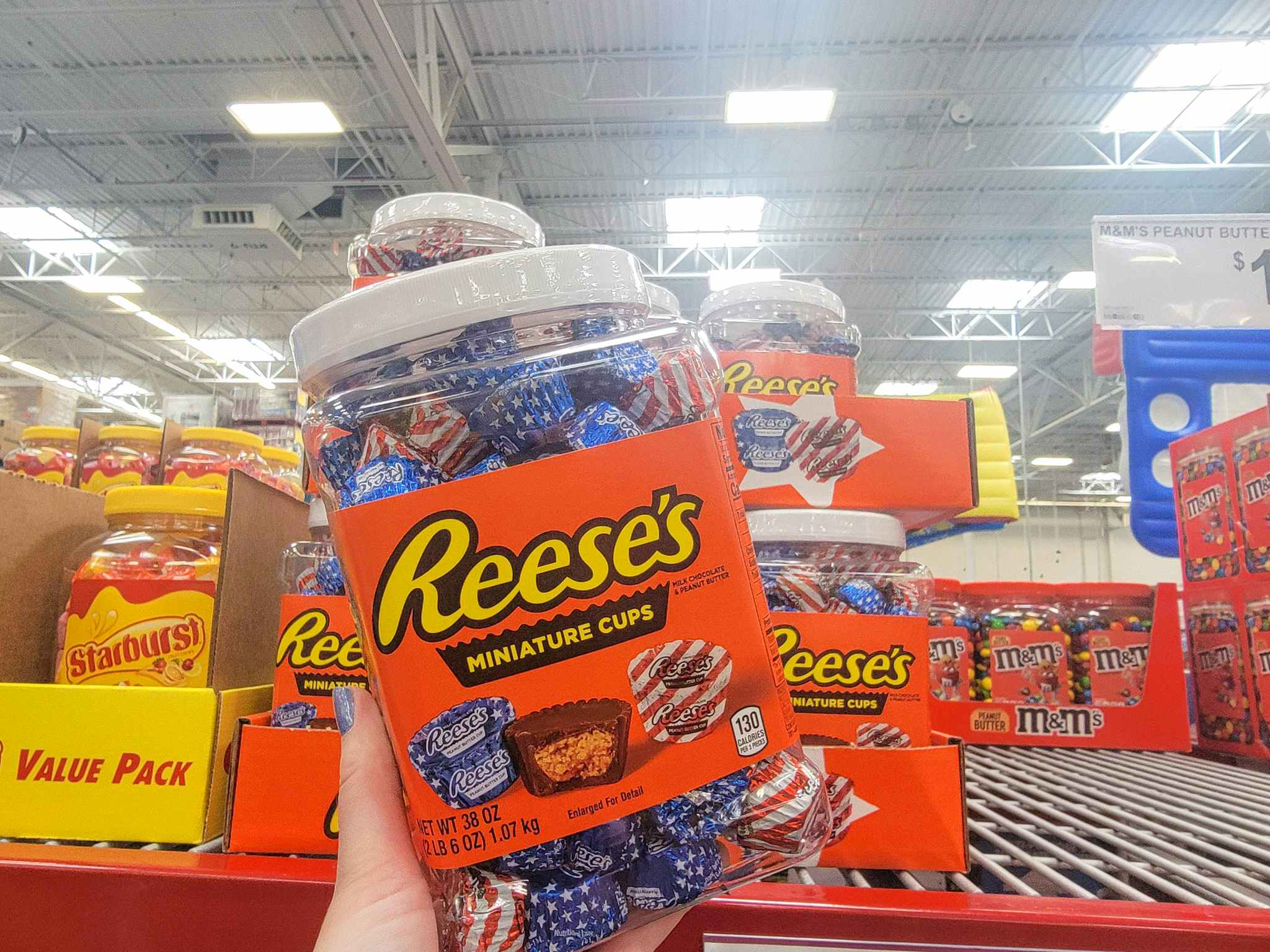 hand holding a large container of reese's