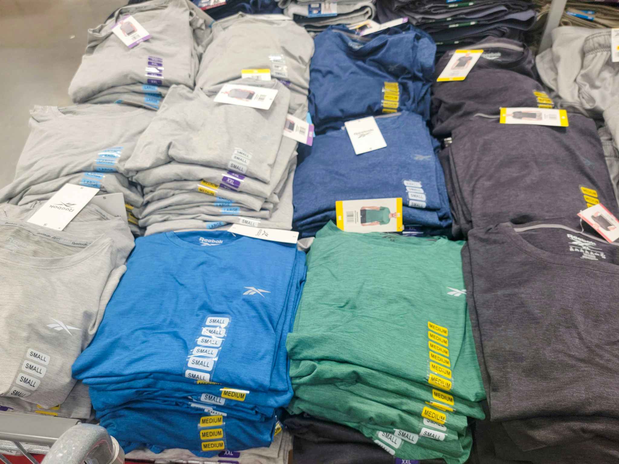 Men's Reebok shirts on a table in a variety of colors