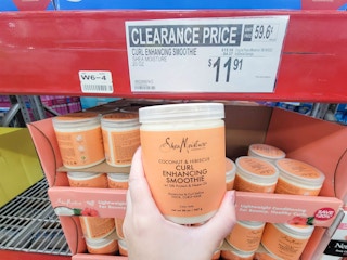 hand holding an orange tub of shea moisture curl enhancing smooothie cream by the clearance sign