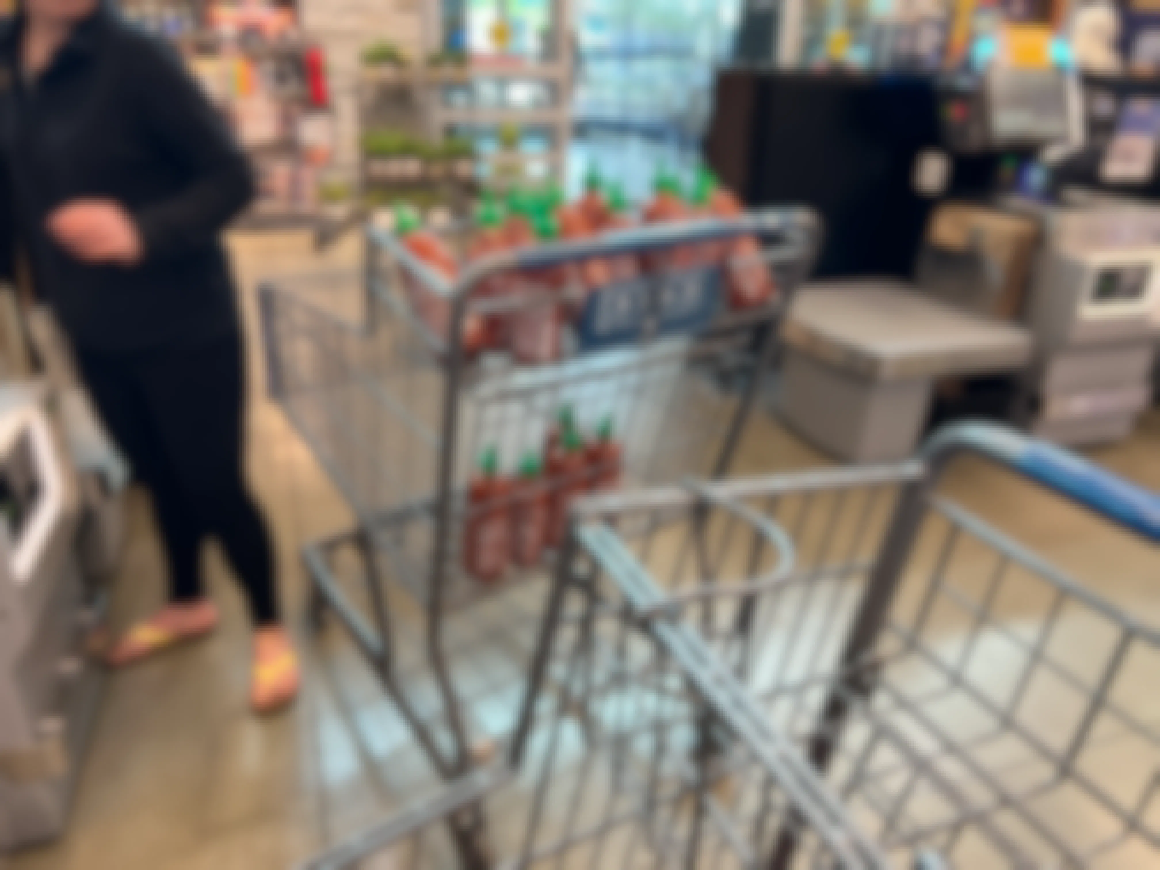 A customer with a cart full of Sriracha bottles in the line at Albertson's checkout.