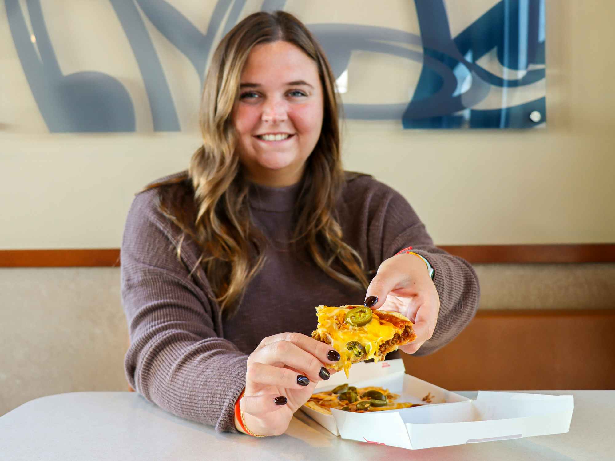 a person holding up a mexican pizza at taco bell