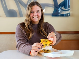 a person holding up a mexican pizza at taco bell