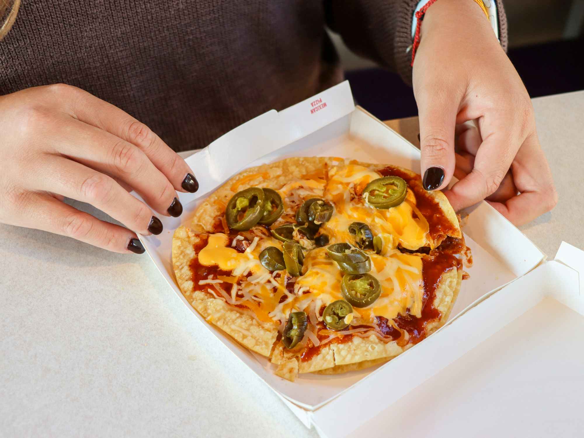 a person touching a mexican pizza at taco bell
