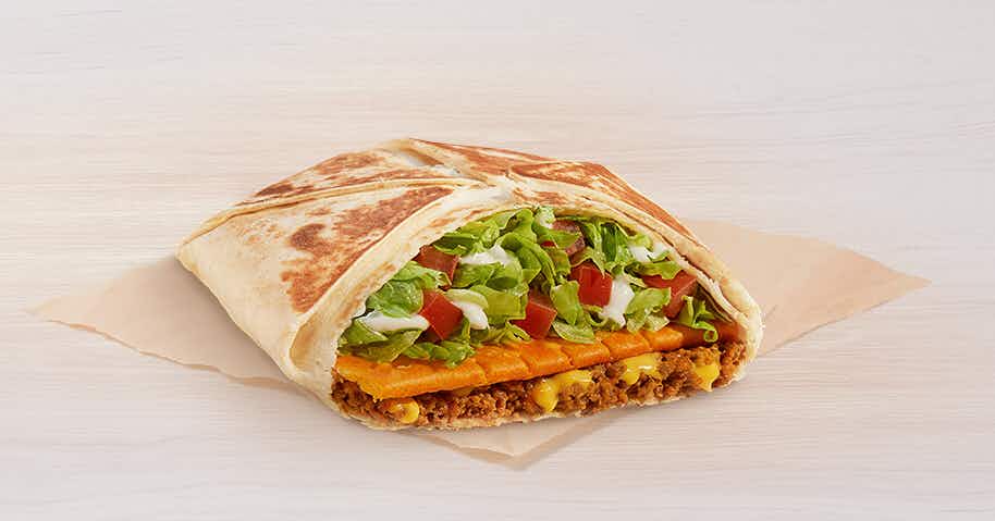 Taco Bell Big Cheez-It Crunchwrap Supreme sitting on a napkin on a table.