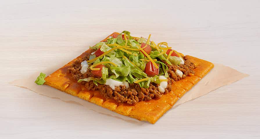 A Taco Bell Cheez-It Tostada sitting on a napkin on a table.