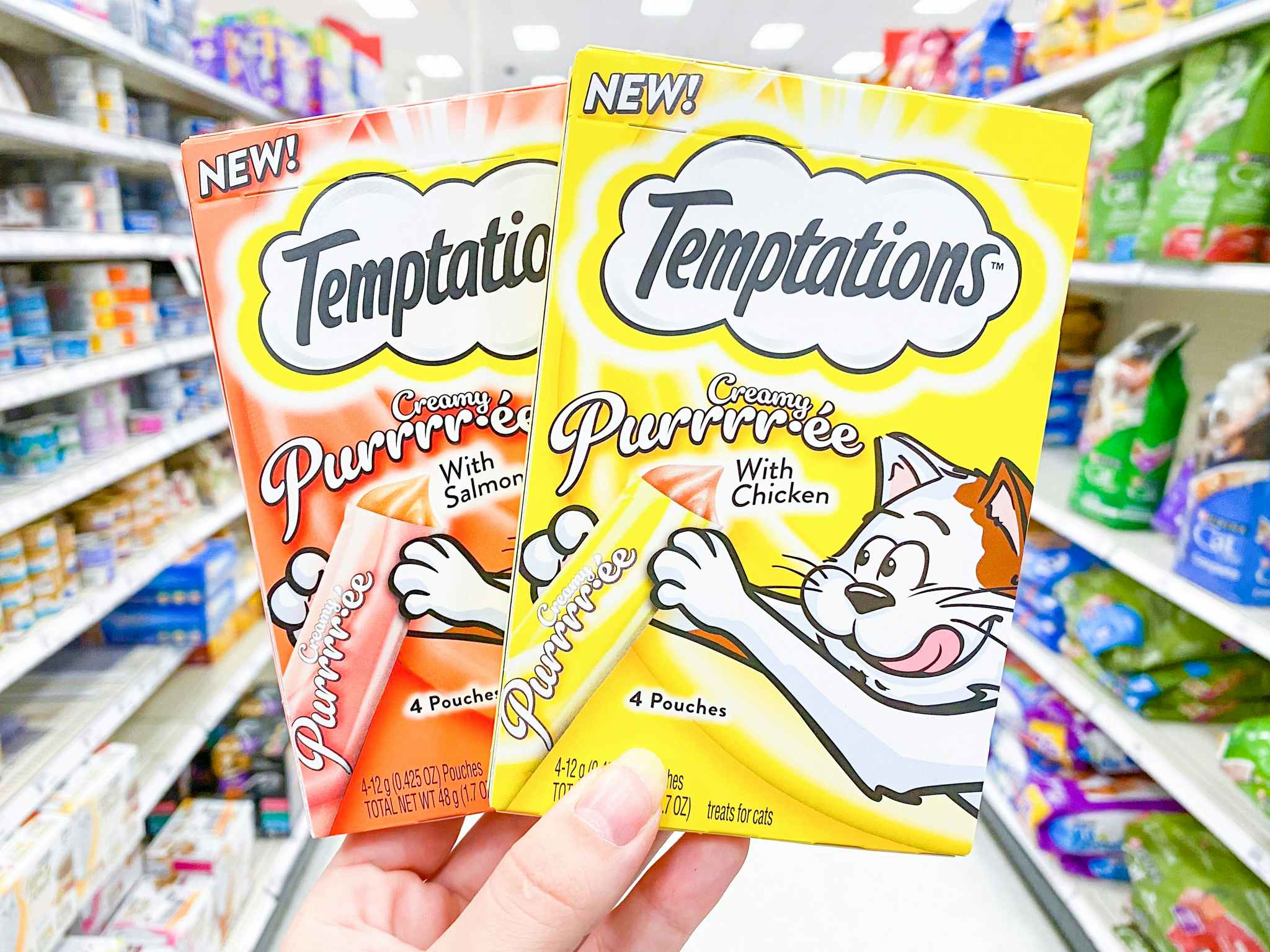 Two packages of Temptations Purre Cat Treats held in pet food aisle at Target